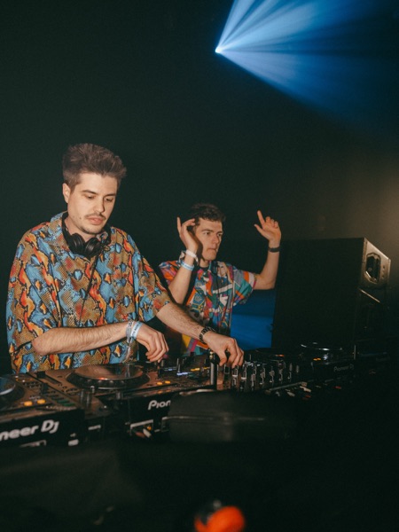 Dj met koptelefoon lacht achter de draaitafels